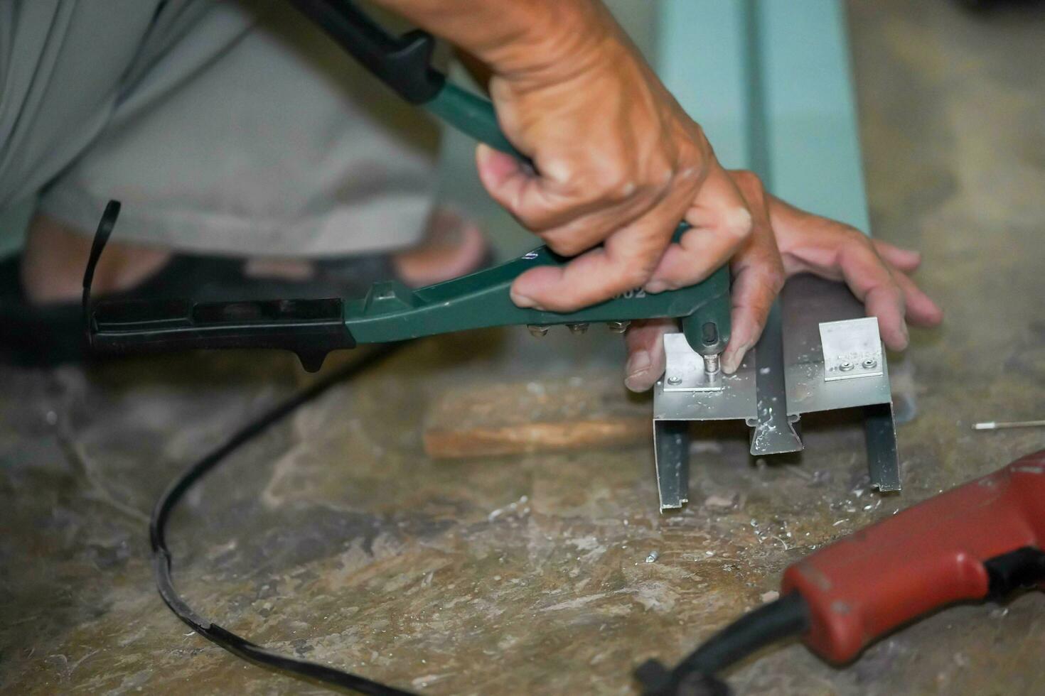 Closeup hands of builder using a eyelet punching aluminum machine working punching aluminum lumber at construction site. photo