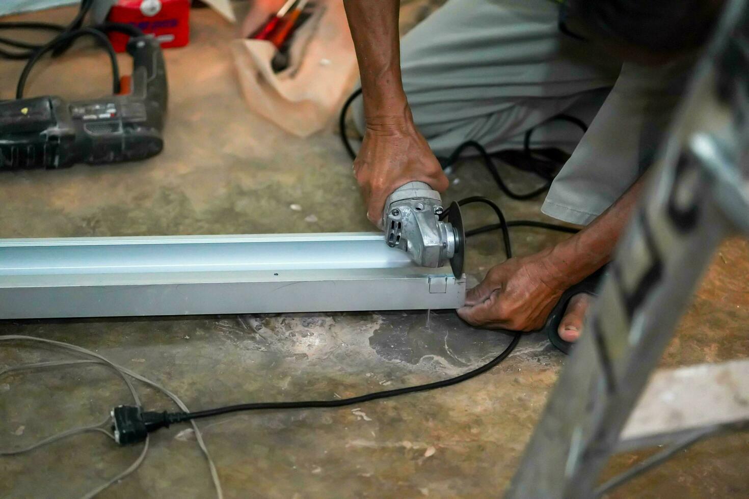 Closeup hands of the master saw the metal holding electric angle grinder working cutting aluminum lumber at construction site. photo