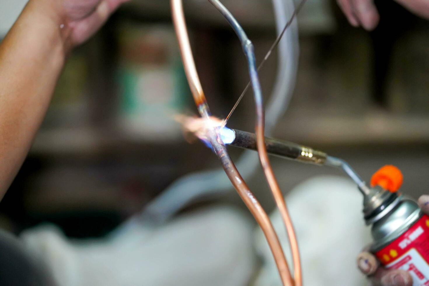 Closeup builder using gas welding to connect the refrigerant pipe. photo