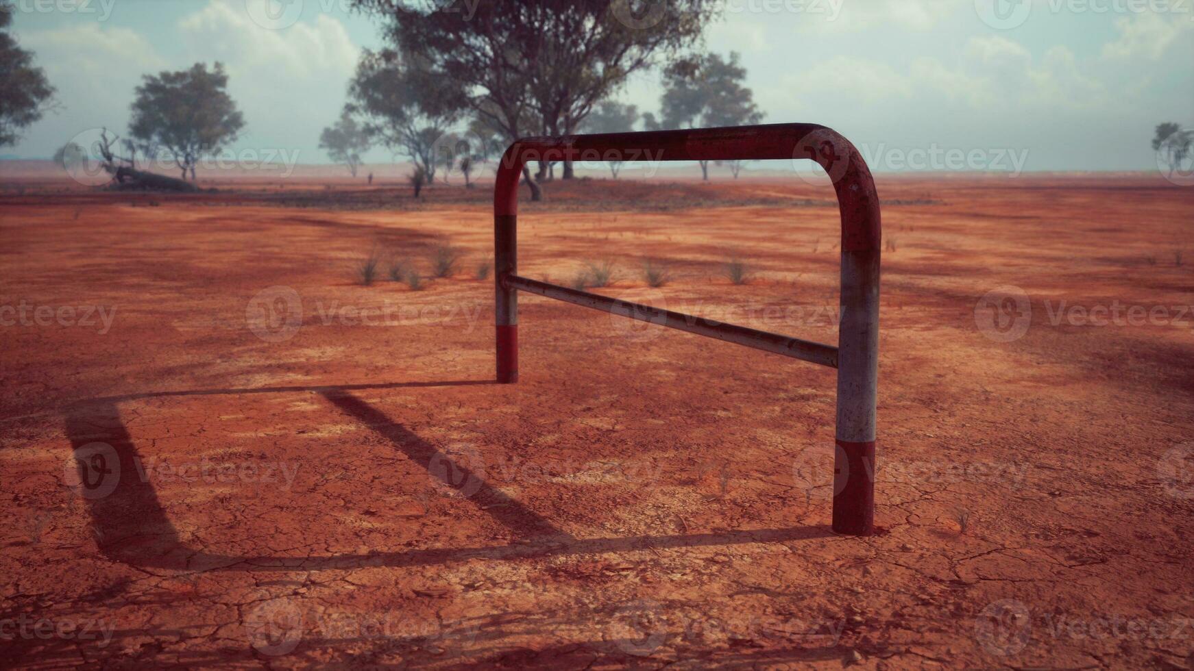 A rustic red dirt field with a charming fence and trees in the background photo