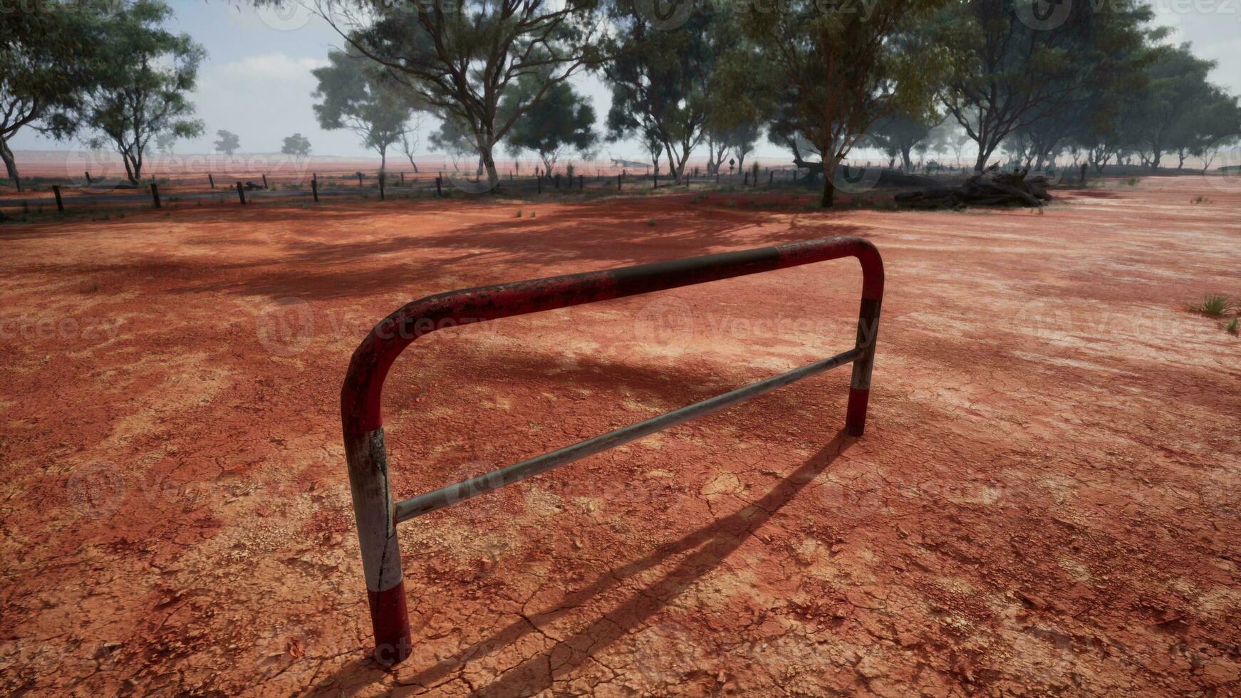 un rústico rojo suciedad campo con un encantador cerca y arboles en el antecedentes foto