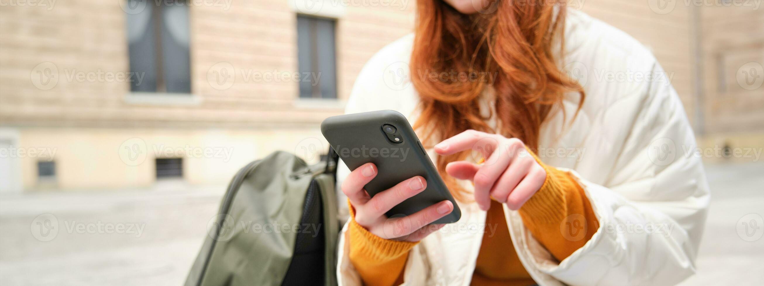 Close up of female hands typing on mobile phone, using smartphone app. GIrl with telephone types, sits outdoors and uses map photo