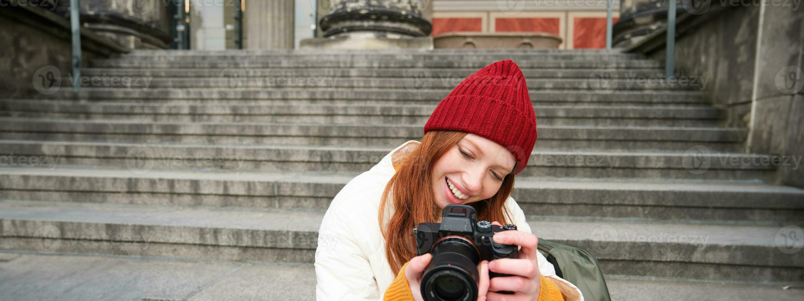 retrato de joven fotógrafo chica, se sienta en escalera con profesional cámara, toma fotos al aire libre, haciendo estilo de vida disparo