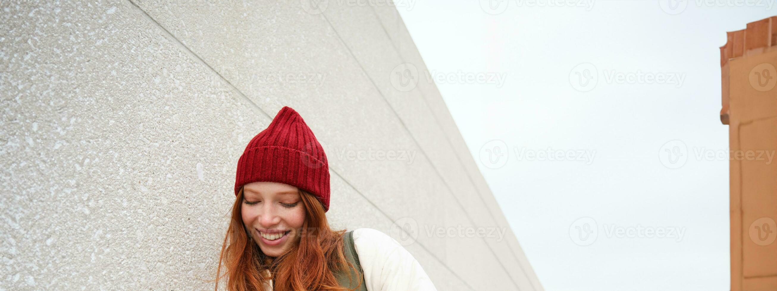Joyful girl tourist looks at mobile phone, texts message on smartphone social media application, walks around city, looks for sightseeing on mobile app photo
