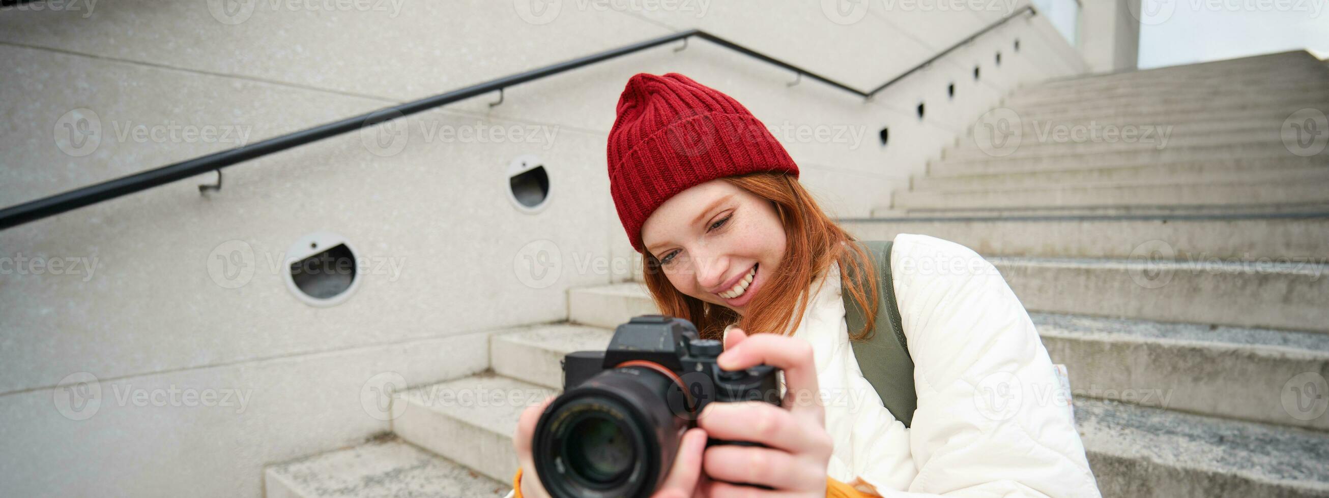 Portrait of female photographer walking around city with professional camera, taking pictures capturing urban shots, photographing outdoors photo