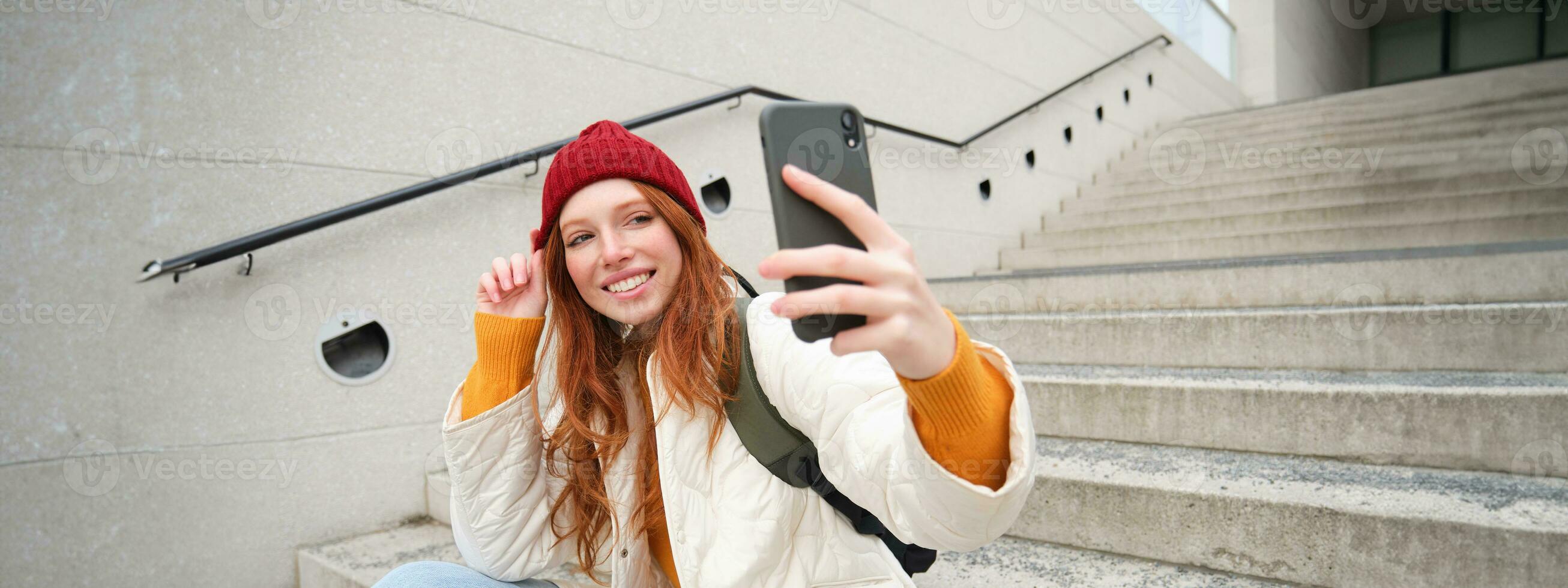 Urban girl takes selfie on street stairs, uses smartphone app to take photo of herself, poses for social media application