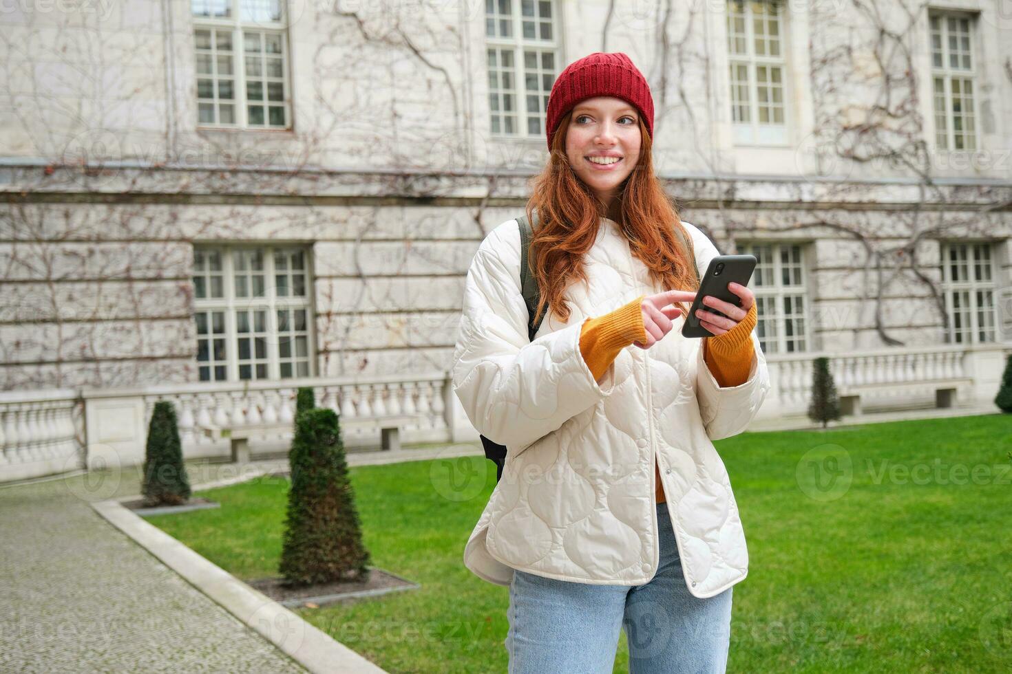 retrato de niña turista, maravillas alrededor ciudad con teléfono inteligente mapa solicitud, participación móvil teléfono y sonriente, mirando arriba informacion en Internet foto