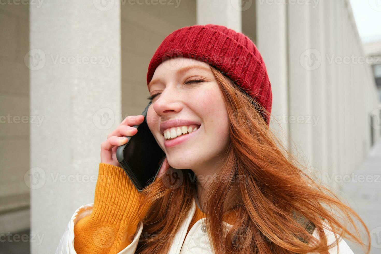 Mobile broadband and people. Smiling young redhead woman walks in town