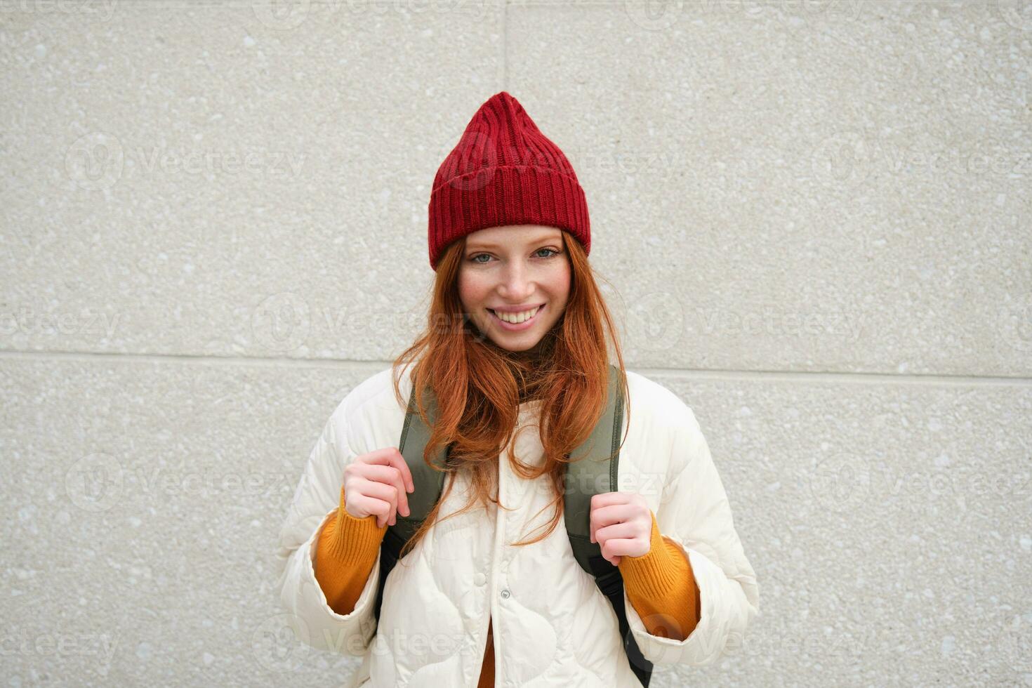 Young stylish girl traveller goes sightseeing, travels around city with backpack, tourist smiles and looks around photo