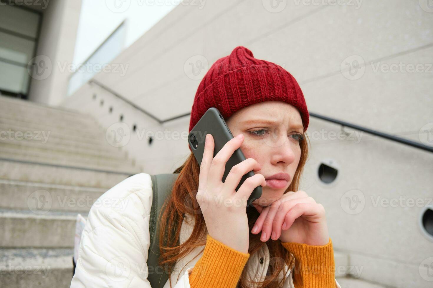 retrato de preocupado niña llamadas alguien con preocupado rostro, siendo en un teléfono, recibe malo noticias, mirando trastornado por conversacion en teléfono inteligente foto
