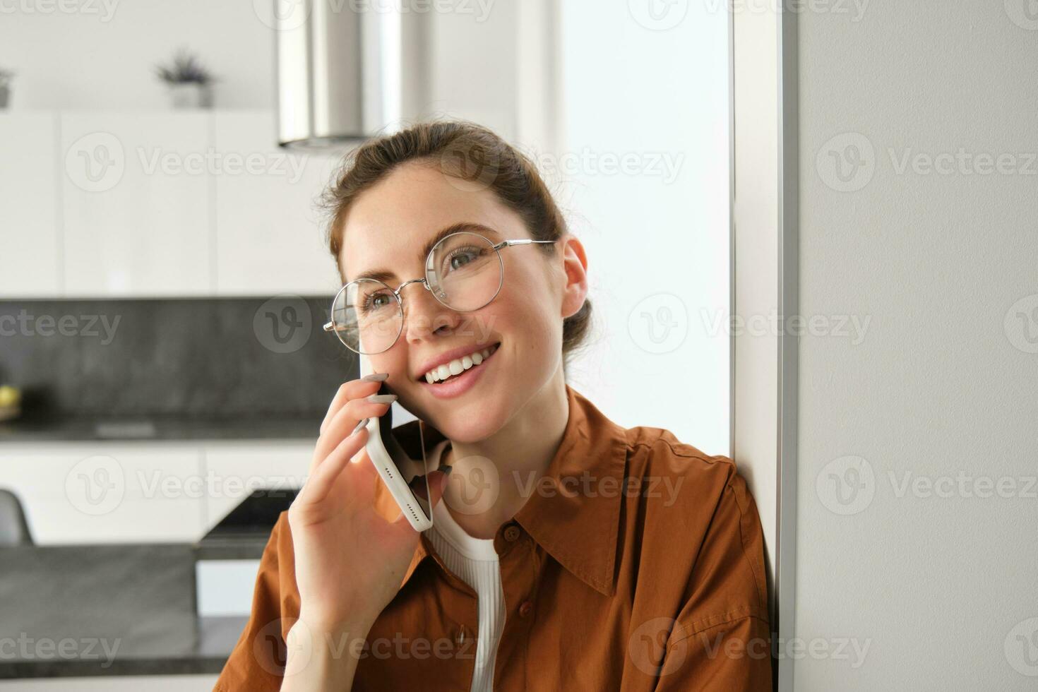 Portrait of happy smiling young woman at home, talking on mobile phone, calling friend and having nice conversation, answer telephone photo
