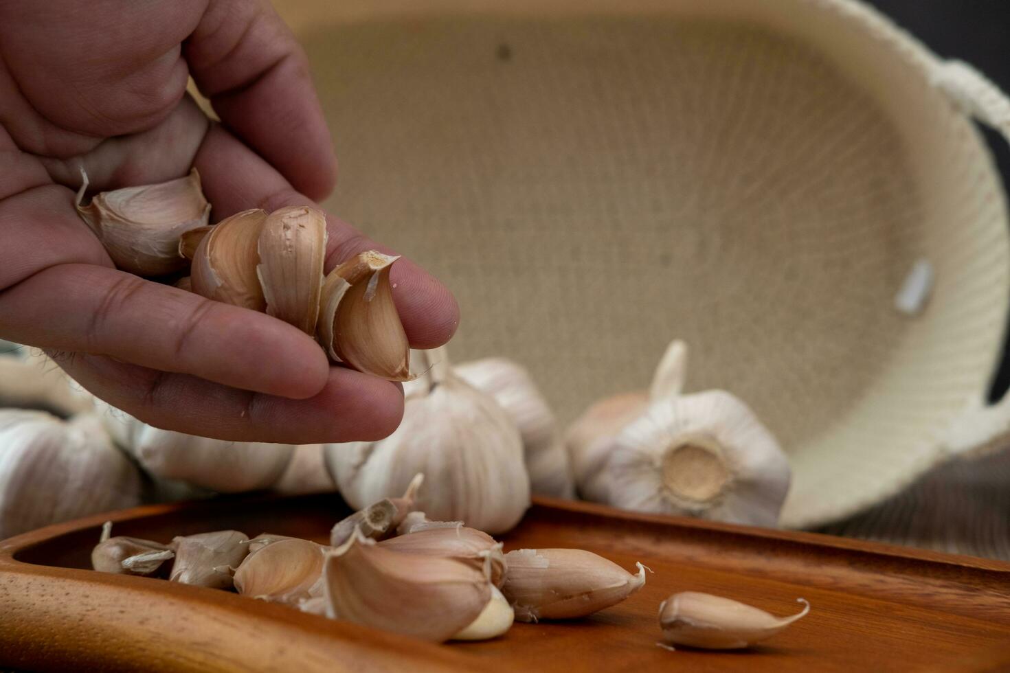 Male hands placing garlic on a wooden plate photo