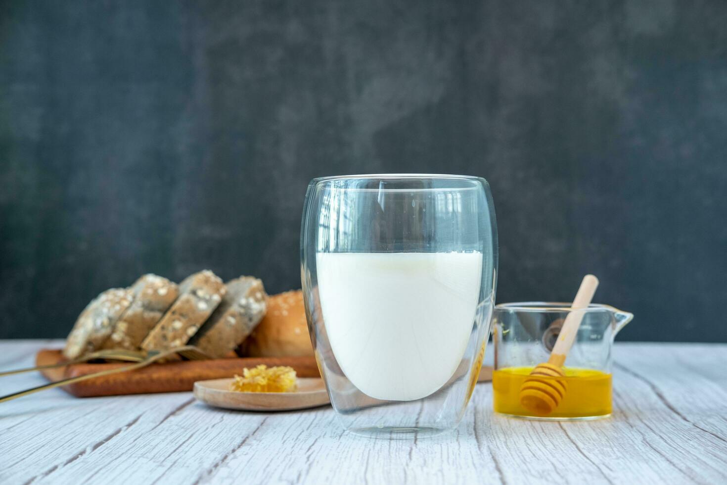 desayuno conjunto miel Leche y un pan en un negro antecedentes foto