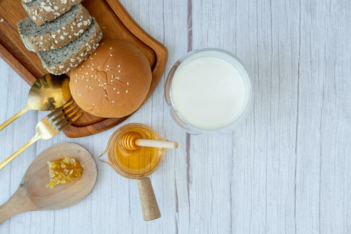 desayuno conjunto miel en un medición taza con un pan y Leche foto