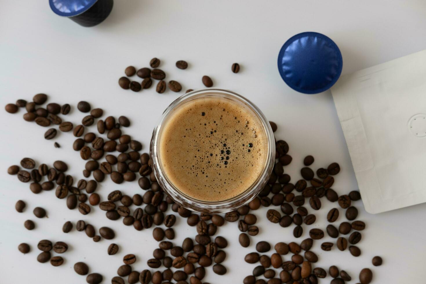 Coffee mug with crema with coffee capsule elements, coffee beans, on a white background. photo