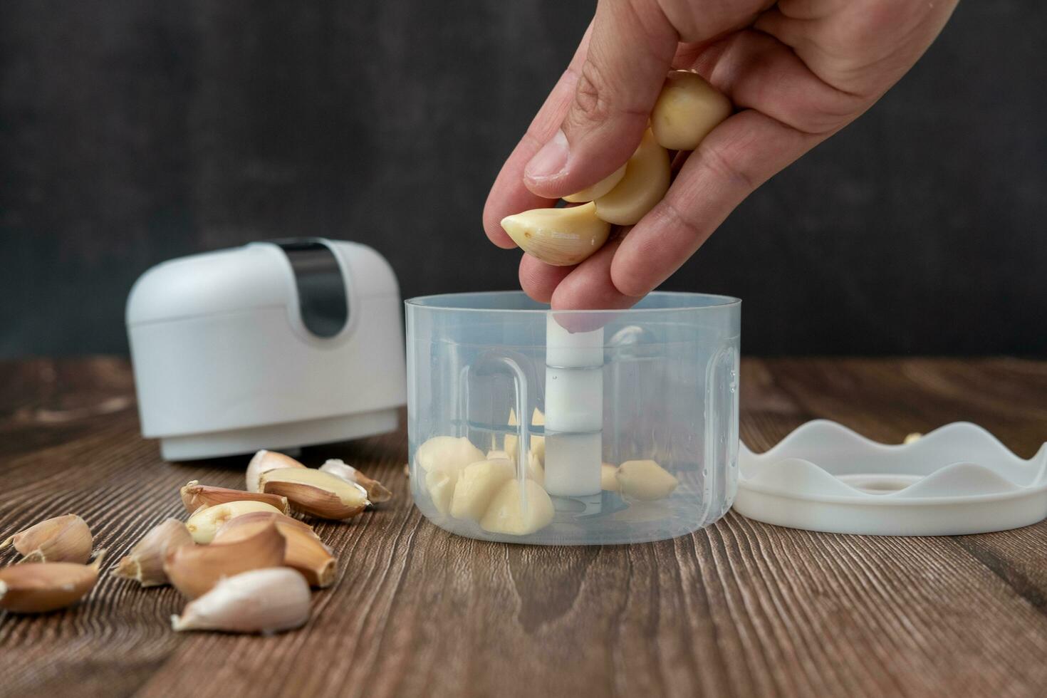 Male hands putting garlic in a blender photo