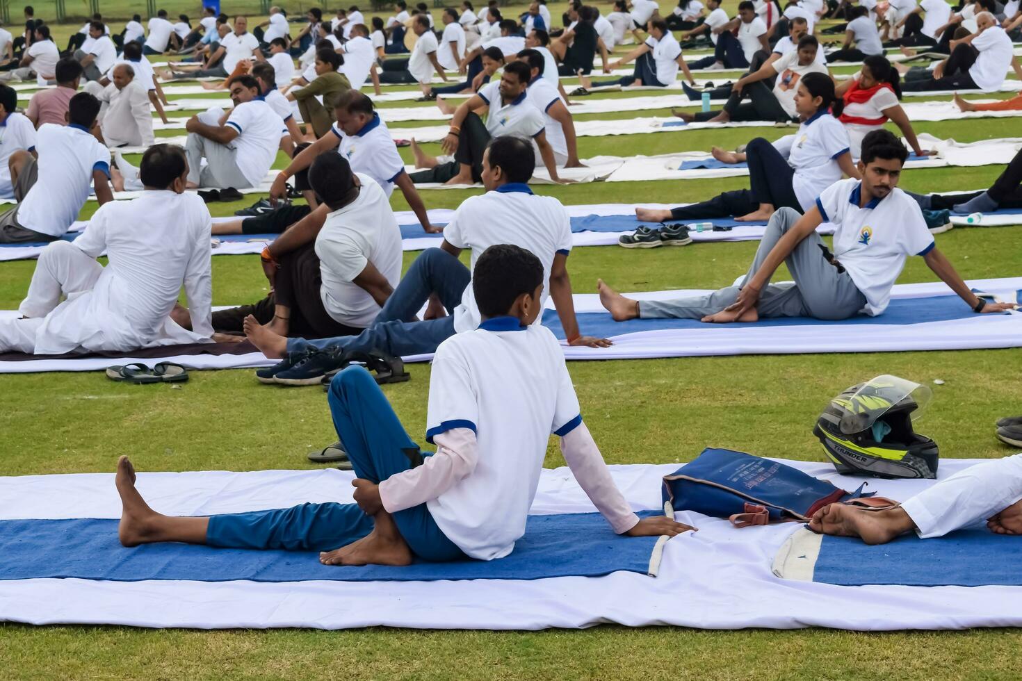 New Delhi, India, June 21, 2023 - Group Yoga exercise session for people at Yamuna Sports Complex in Delhi on International Yoga Day, Big group of adults attending yoga class in cricket stadium photo