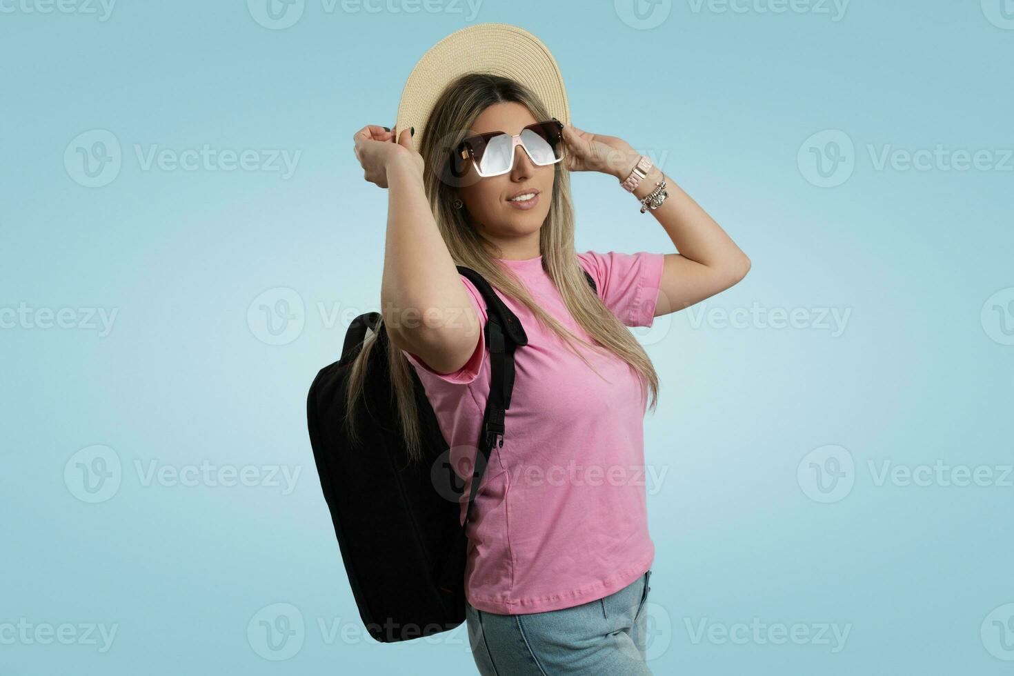 Smiling Woman in Casual Clothing with Blue Cap and Sunglasses Against Colored Backdrop photo