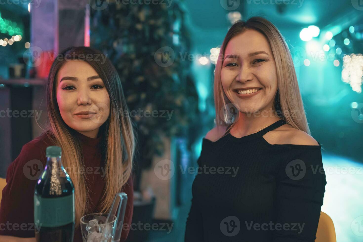 Two pretty women at cafe table looking at camera. photo