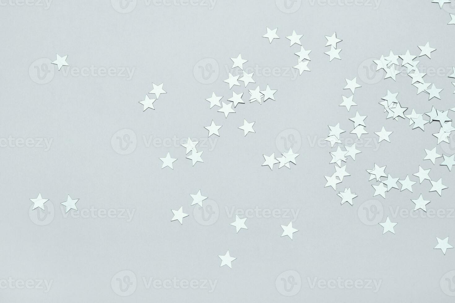Silver stars confetti on gray background. Christmas or winter festive background photo