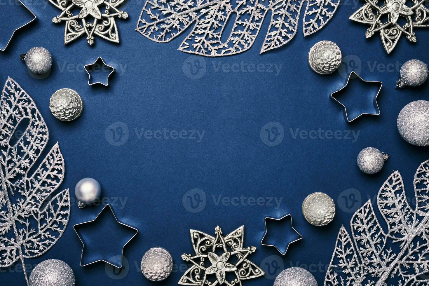 Christmas blue background. Shining silver pattern frame made of frost decorative leaves and baubles photo