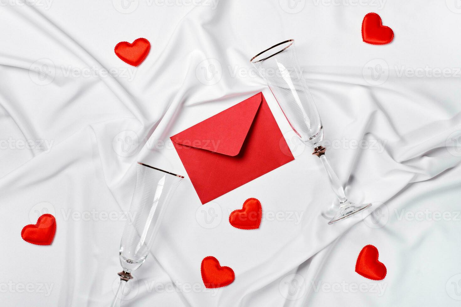 Romantic concept. Valentines day background. Red envelope, champagne glasses and hearts on white silk sheet photo