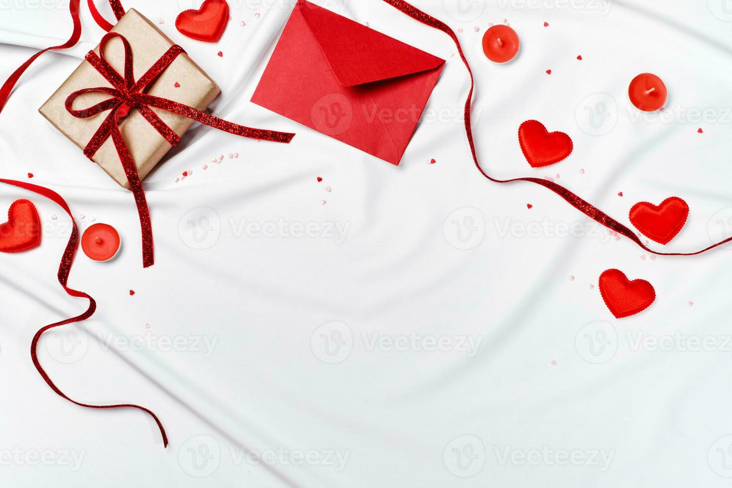 Romantic concept. Valentines day background. Red envelope, Gift box and hearts on white silk sheet photo