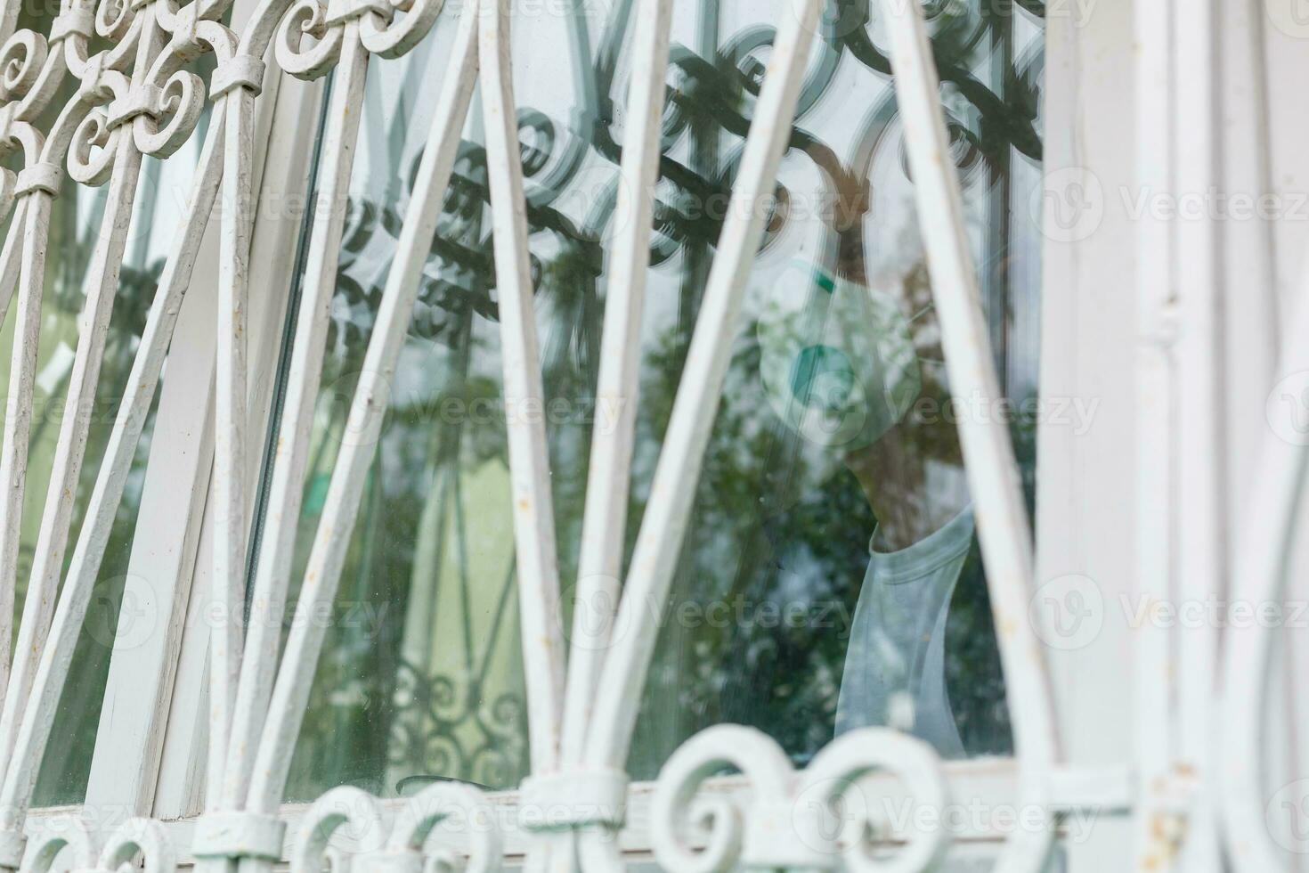 Coronavirus quarantine. Senior man wearing protective mask behind the window stay at home to avoid contagion by COVID-19 - responsibility and prevention concept photo