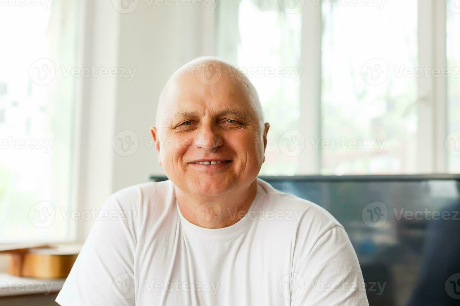 Elderly man with headphones and computer laughing happily, telework, e-business or commerce, customer support representative, video-chat, copy space photo