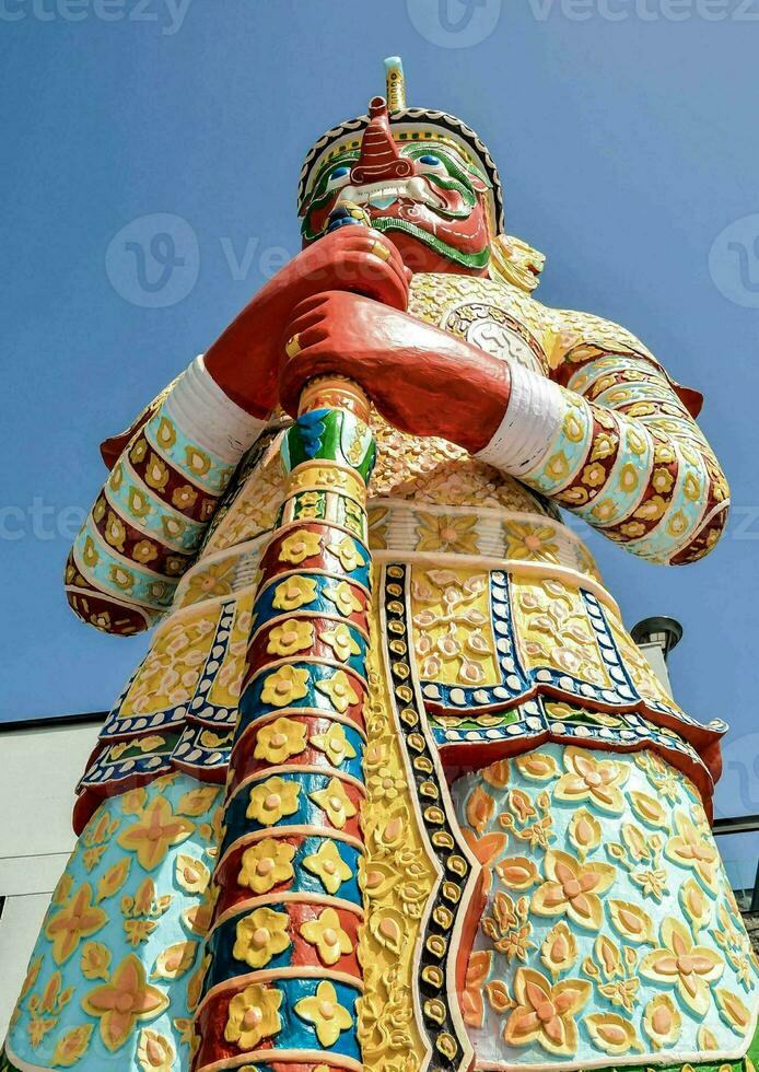 a colorful statue of a man holding a stick photo
