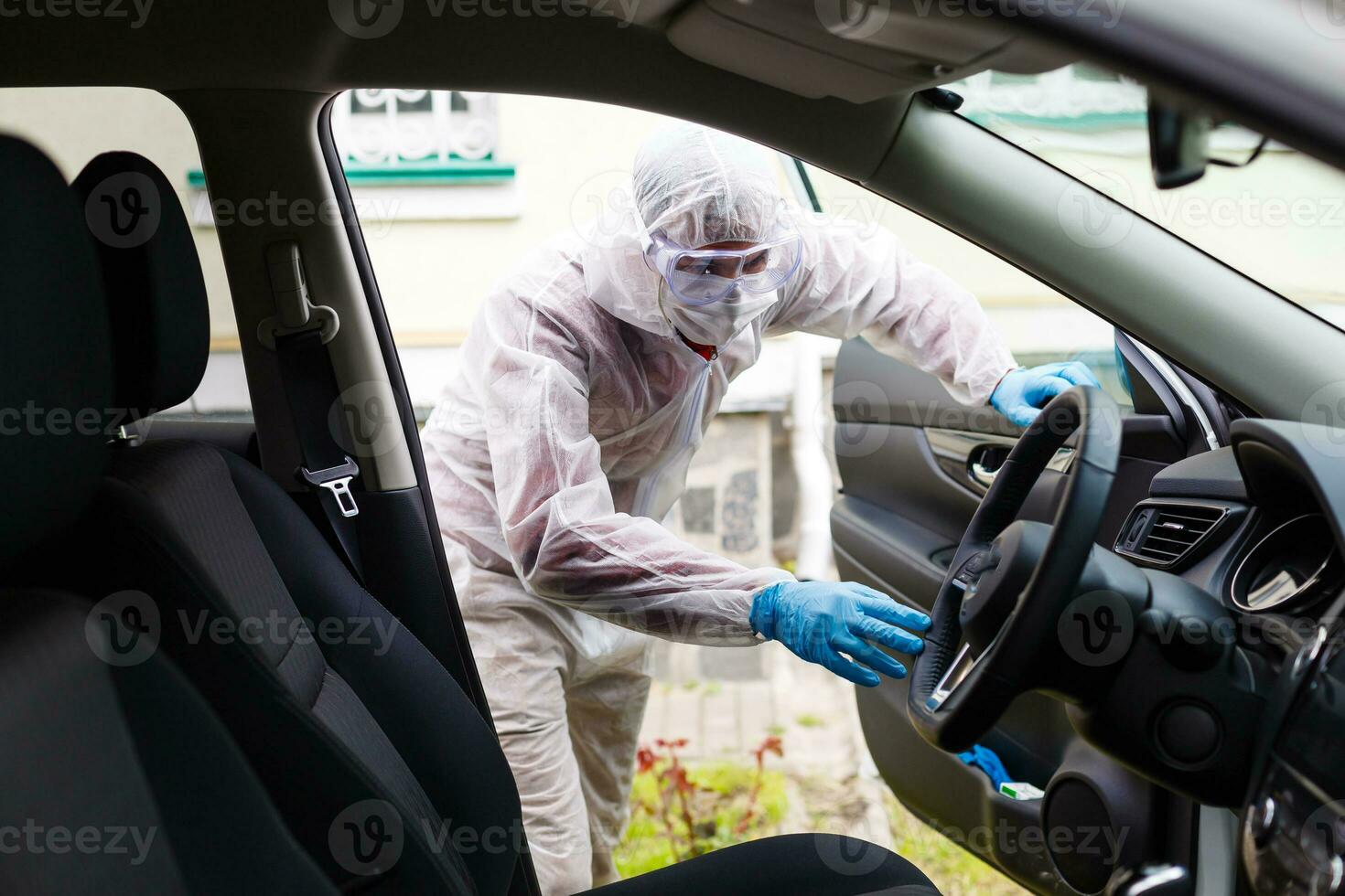 Disinfectant worker character in protective mask and suit sprays bacterial or virus in a car. photo