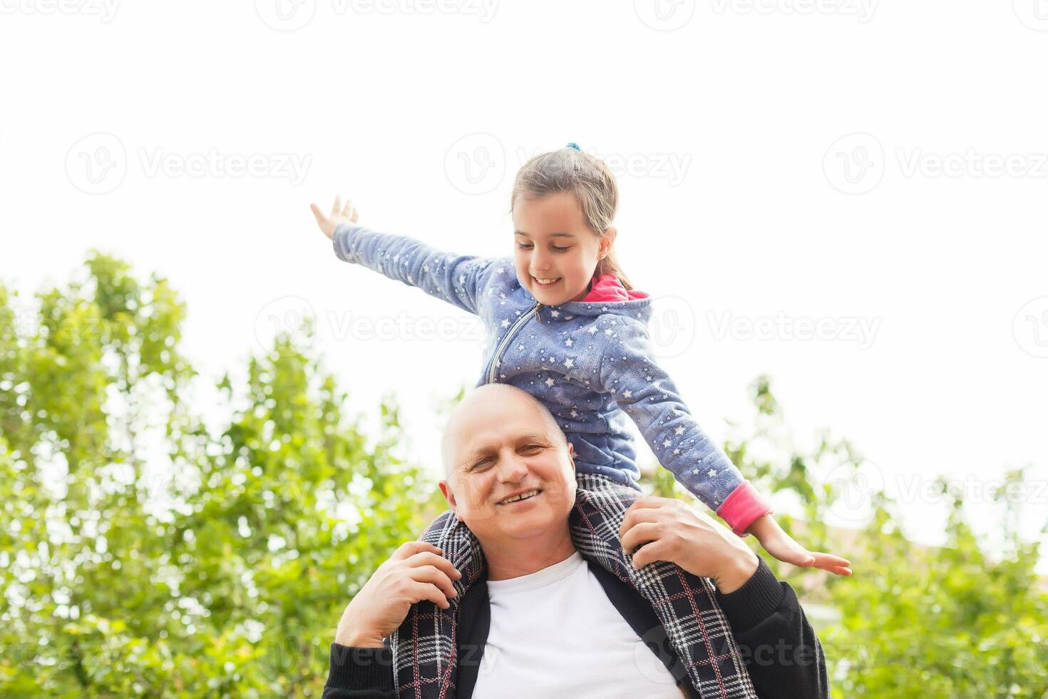 retrato de pequeño niña con mayor abuelo en el patio interior jardín, de pie. foto