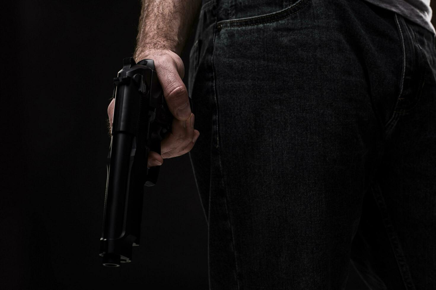 Killer with gun on black background at the studio photo