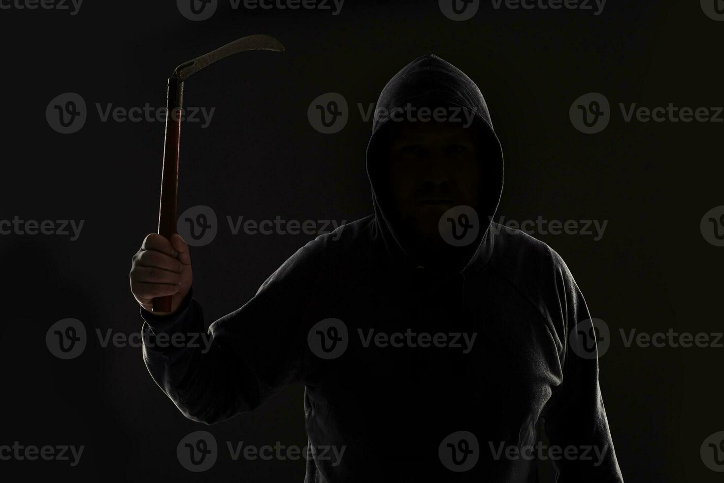 Criminal in dark clothes and balaclava with scythe photo