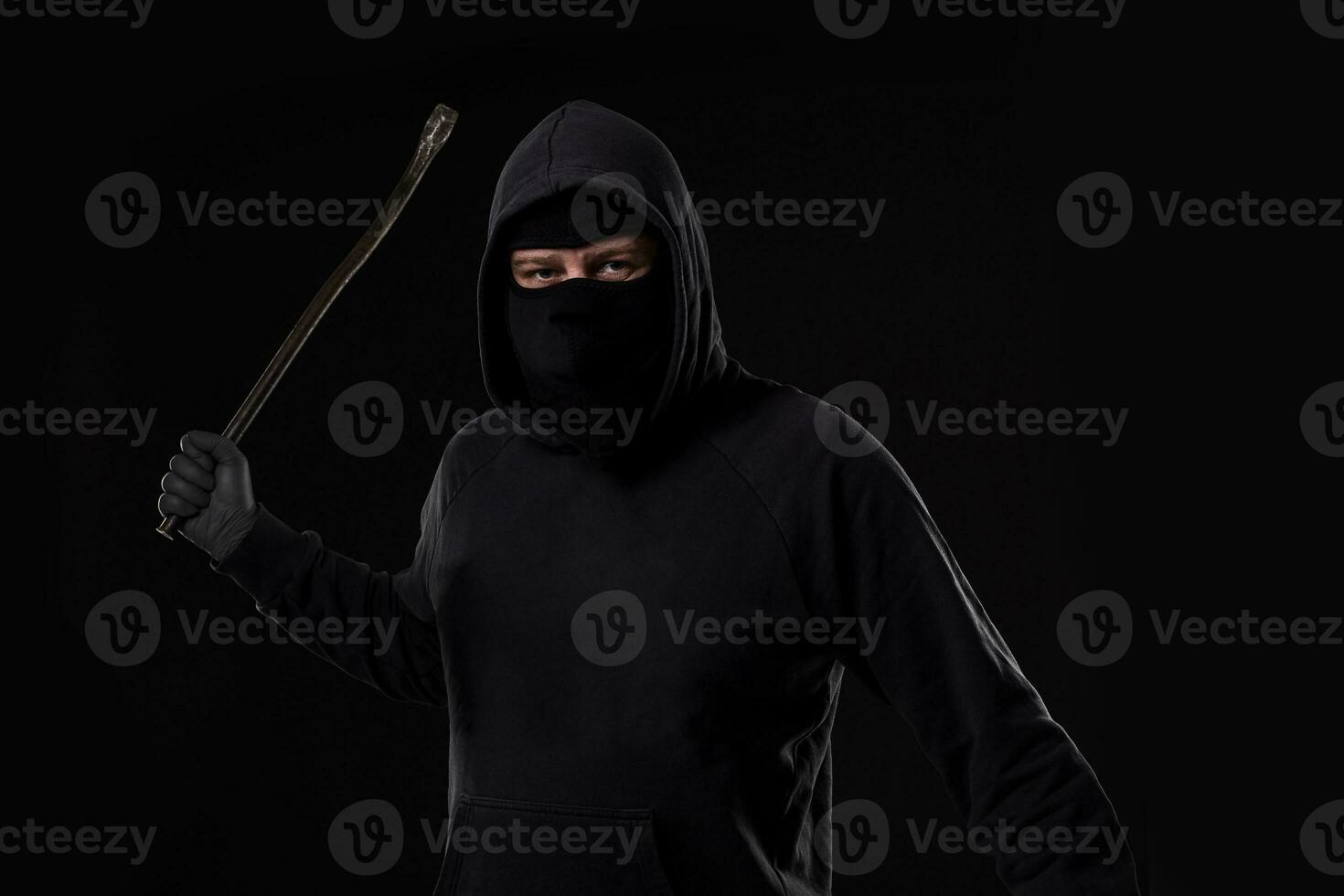 Male offender masked with a scrap. On black background at the studio photo