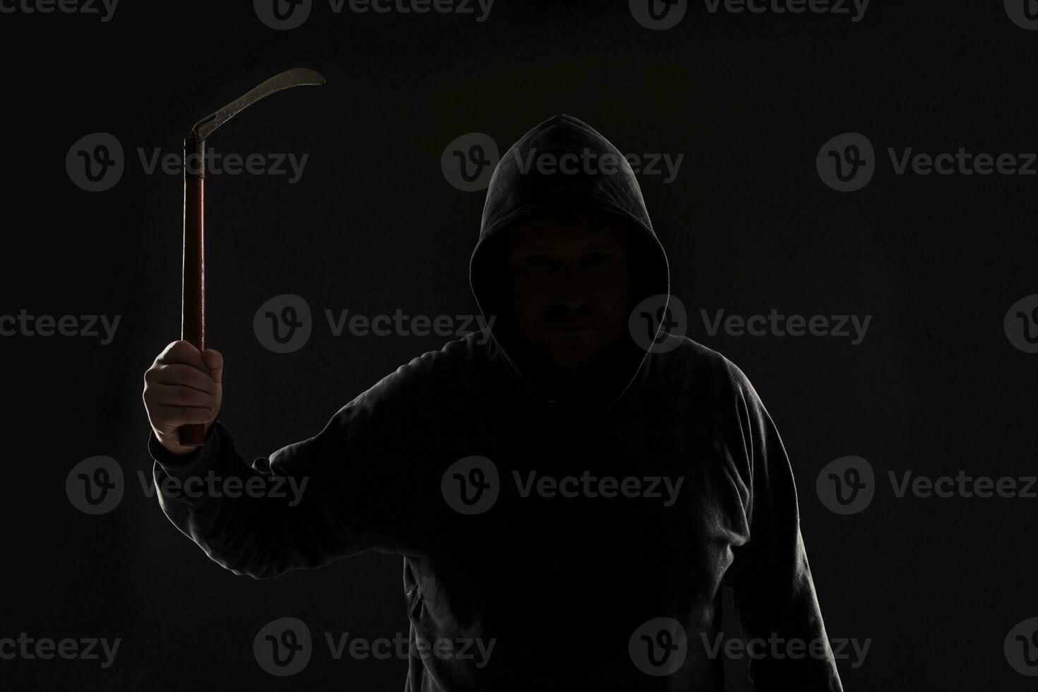 Criminal in dark clothes and balaclava with scythe photo