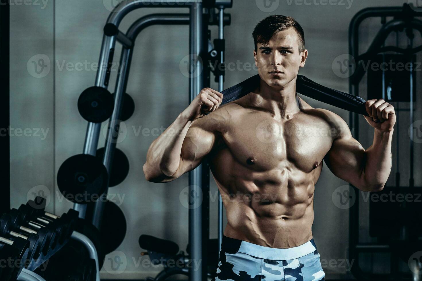 Young muscular man with a towel around his neck after training at the gym photo