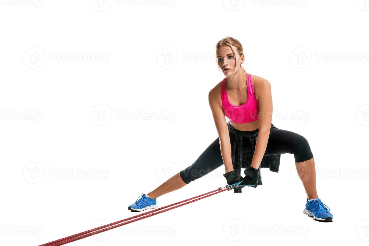 Strong woman using a resistance band in her exercise routine. Young woman performs fitness exercises on white background. photo