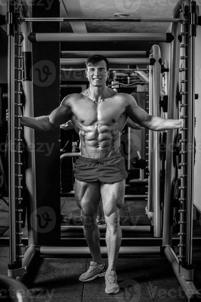 Handsome man with big muscles, posing at the camera in the gym photo