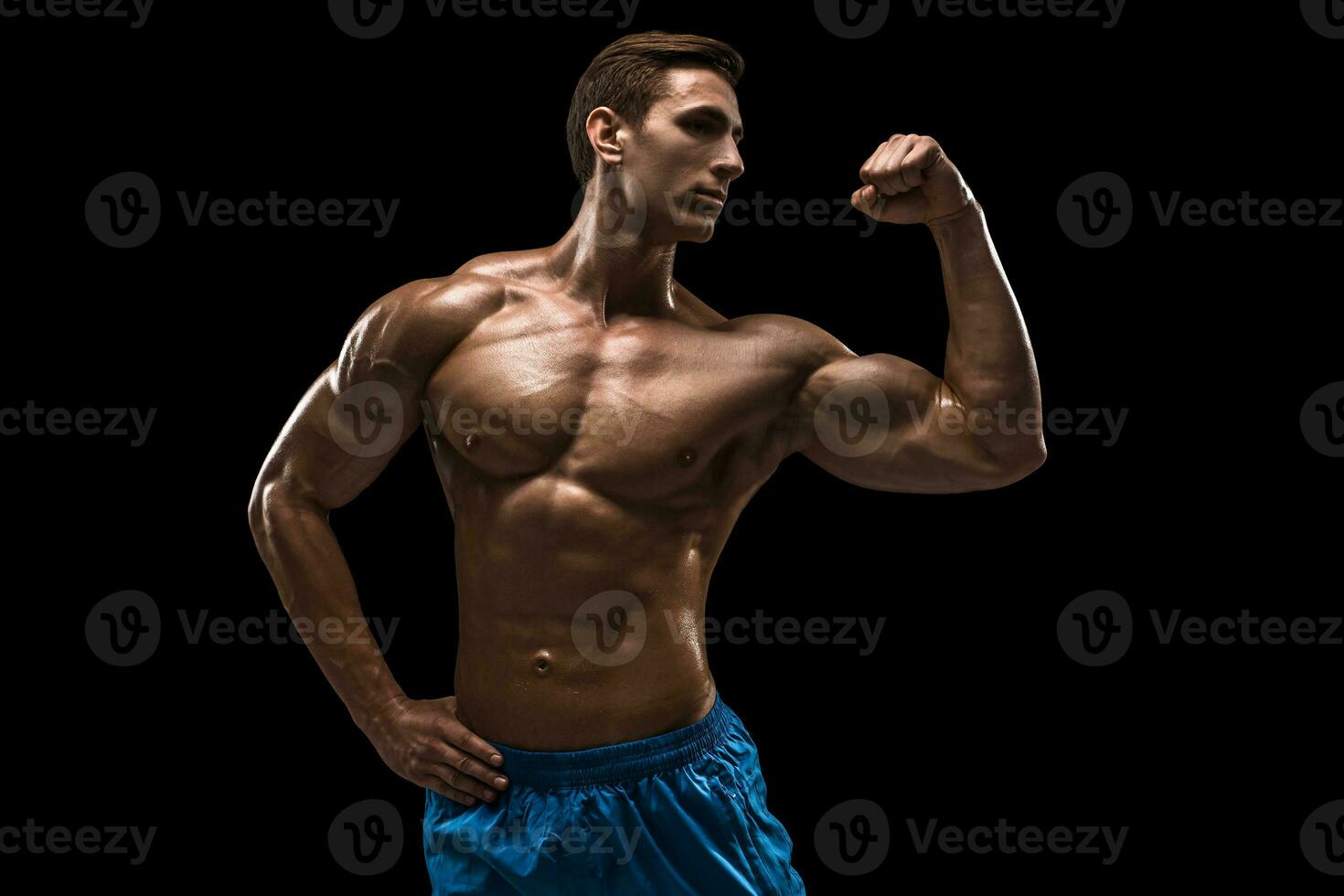 Muscular and fit young bodybuilder fitness male model posing over black background. photo