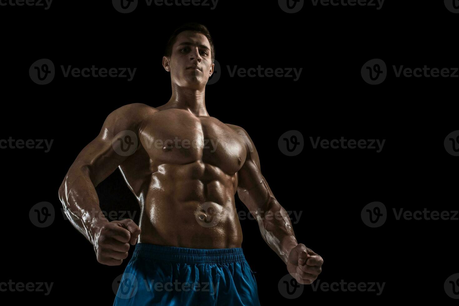 Muscular and fit young bodybuilder fitness male model posing over black background. photo