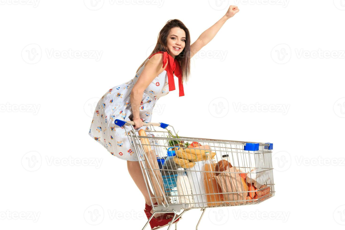 Woman with shopping cart full with products isolated over white background photo