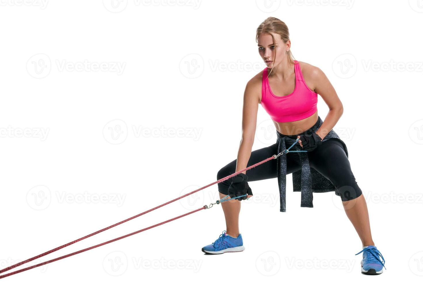 Strong woman using a resistance band in her exercise routine. Young woman performs fitness exercises on white background. photo