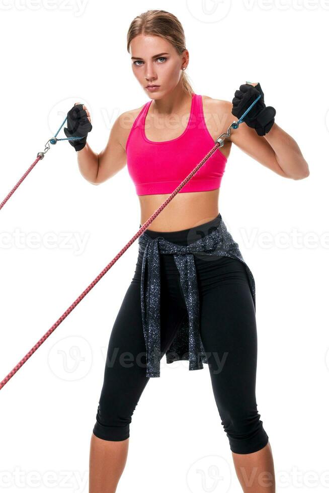 Strong woman using a resistance band in her exercise routine. Young woman performs fitness exercises on white background. photo
