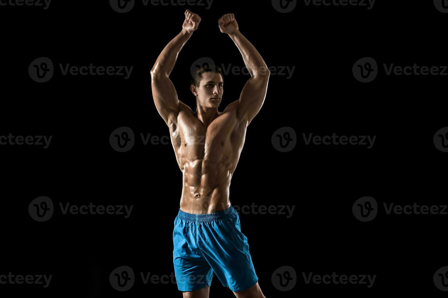Muscular and fit young bodybuilder fitness male model posing over black background. photo