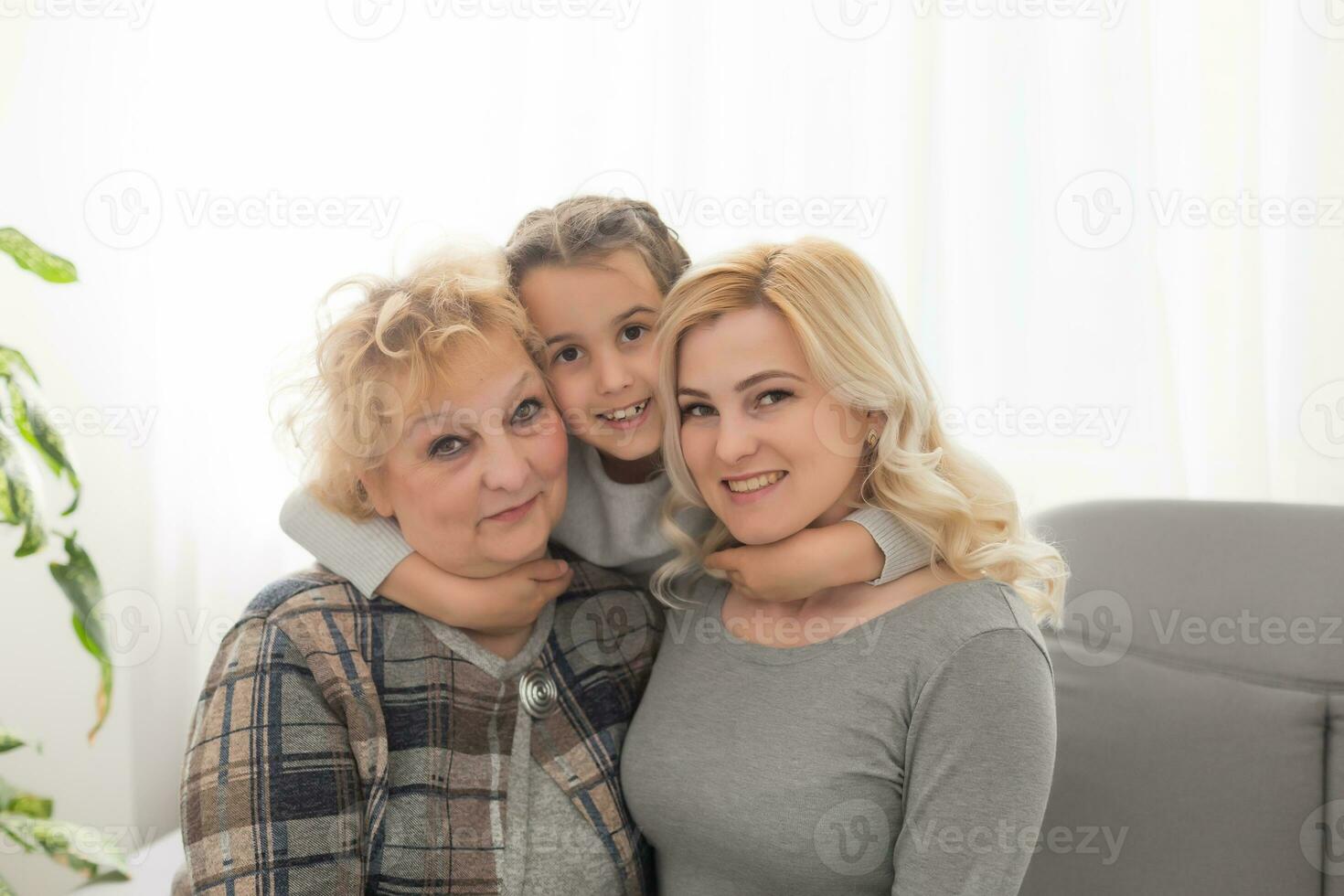 Portrait of three generations of women look at camera posing for family picture, cute little girl hug mom and granny enjoy time at home, smiling mother, daughter and grandmother spend weekend together photo