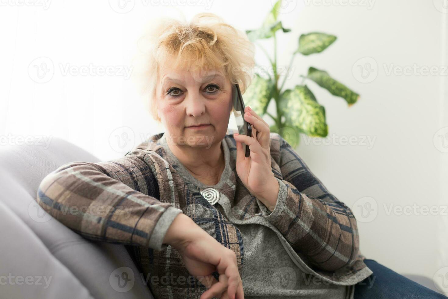 Happy senior woman talking on smartphone at home. photo