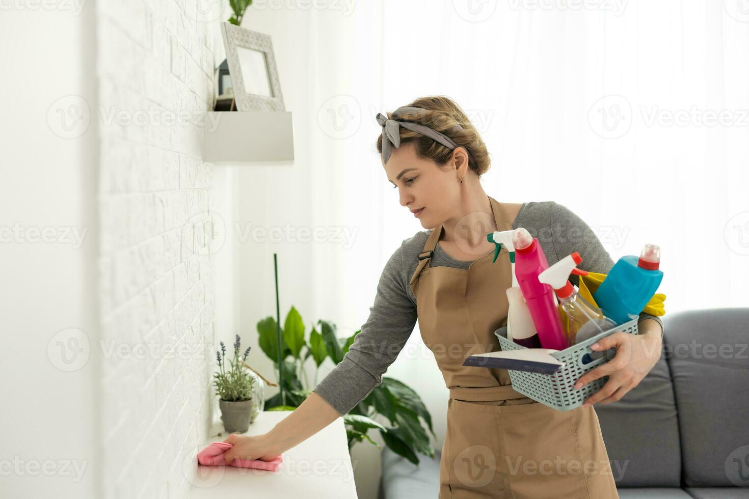 Woman cleaning and polishing the kitchen worktop with a spray detergent, housekeeping and hygiene concept. photo