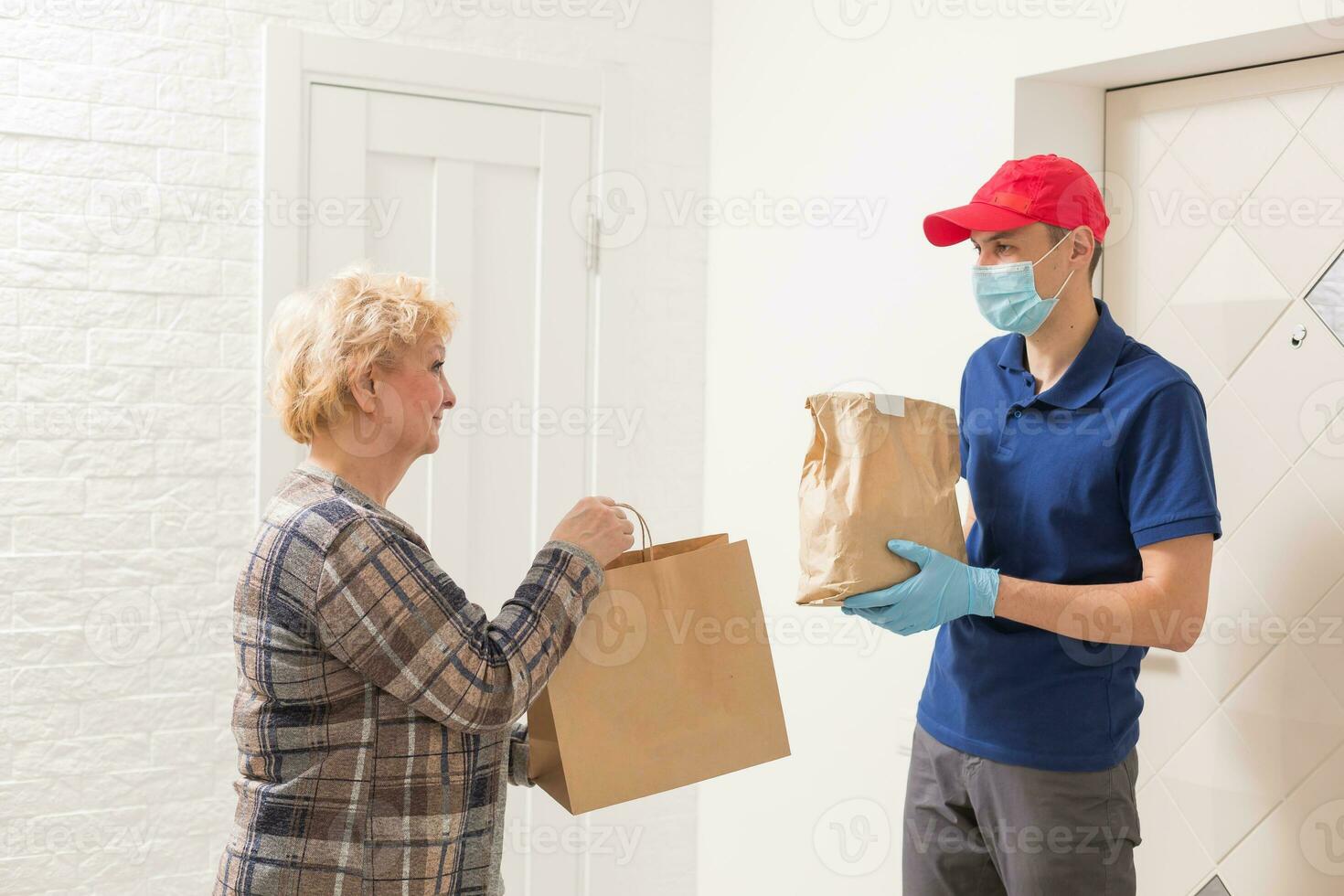 An elderly woman stays at home. Food delivery in a medical mask. photo