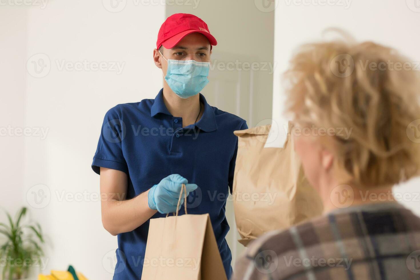 An elderly woman stays at home. Food delivery in a medical mask. photo